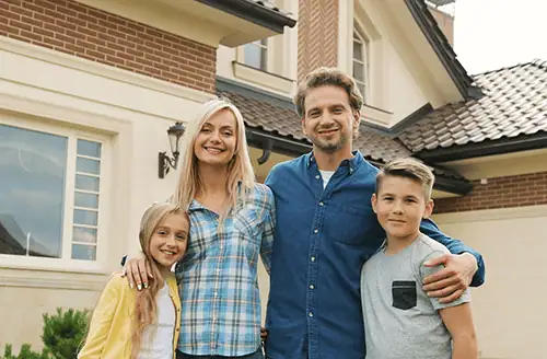 Happy Family in Front of House with Gutters
